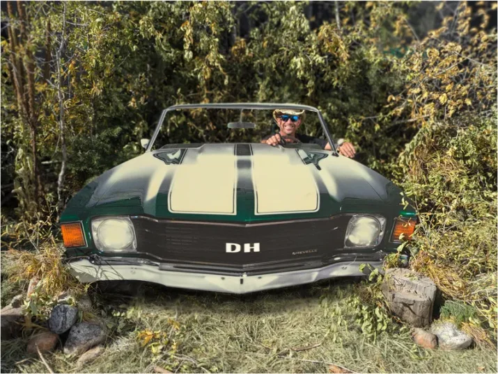 Derek Hogeland leaning out of his classic muscle car, DH plates